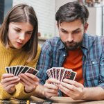 serieux-jeune-couple-regarder-leurs-cartes-jouer-jeu-plateau